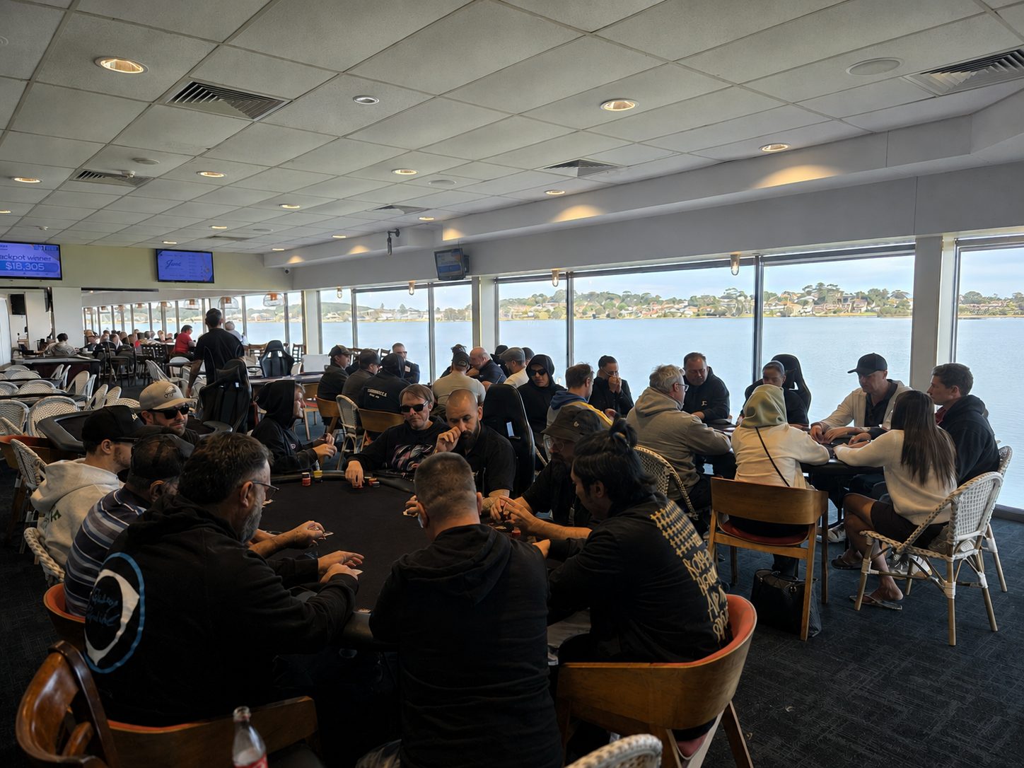 Players in a 124 Poker tournament at full tables in a waterfront venue